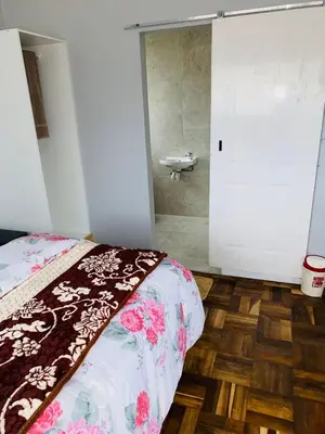 a bedroom with a bed and a bathroom with a shower at 22clyde street bostin in Cape Town