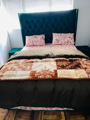 a bed with a blue head board and pink pillows at 22clyde street bostin in Cape Town