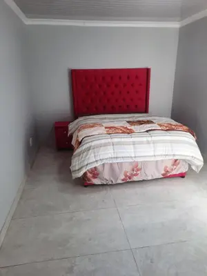 a bed with a red headboard in a bedroom at 22clyde street bostin in Cape Town