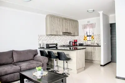 a living room with a couch and a kitchen at 7 on Laibach - Buhrein Estate, Kraaifontein in Cape Town