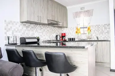 a kitchen with a counter with black leather chairs at 7 on Laibach - Buhrein Estate, Kraaifontein in Cape Town