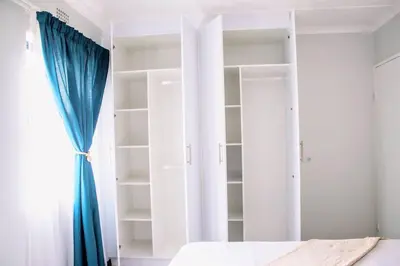 a bedroom with white shelves and a bed and a window at 7 on Laibach - Buhrein Estate, Kraaifontein in Cape Town