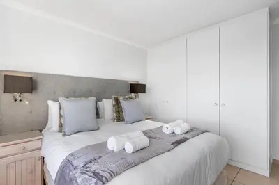 a bedroom with a large white bed with towels on it at The Waves 302 in Cape Town