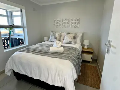 a bedroom with a bed and a window at Seaside Serenity in Hermanus