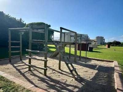a playground with a wooden swing set in a park at Seaside Serenity in Hermanus