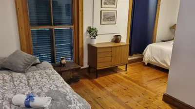 a bedroom with a bed and a dresser and two windows at Château Naudé in Stellenbosch Free Secure Parking in Stellenbosch