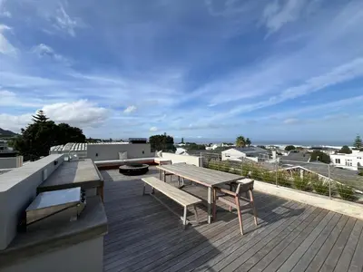 a deck with a picnic table and benches on a roof at The Hermanus Retreat in Hermanus