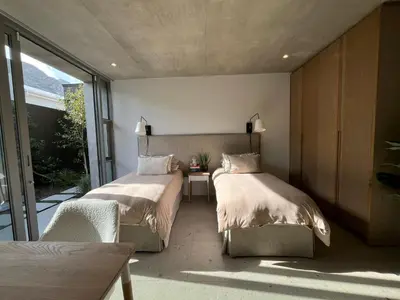 a bedroom with two beds and a table and a window at The Hermanus Retreat in Hermanus