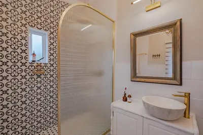 a bathroom with a shower with a sink and a mirror at Blue Bell in Hermanus