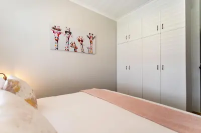a bedroom with white cabinets and a bed at Bayview 307 in Hermanus