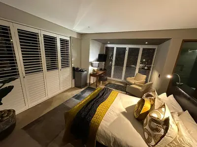 a bedroom with a king sized bed and a chair at Luxury Vineyard Suites in Cape Town