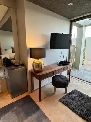 a room with a desk with a television and a lamp at Luxury Vineyard Suites in Cape Town