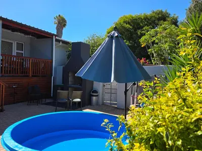 a patio with a blue pool and an umbrella at 35 Amanda - Durbanville in Cape Town
