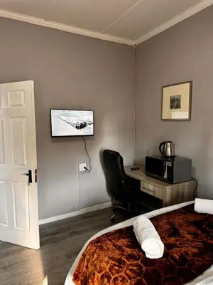a bedroom with a bed and a desk and a television at Mila Lodge 2 in Goodwood