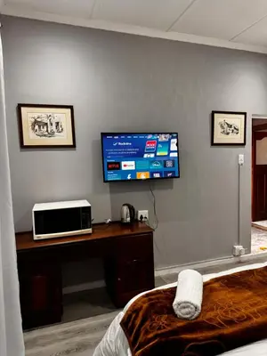 a room with a tv on a wall with a desk at Mila Lodge 2 in Goodwood