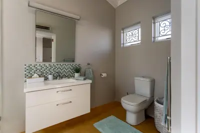 a bathroom with a toilet and a sink and a mirror at Plaisir du Cap in Hermanus