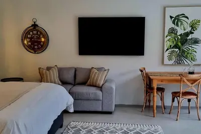 a bedroom with a couch and a table and a tv at C'est la Vie 3 in Franschhoek