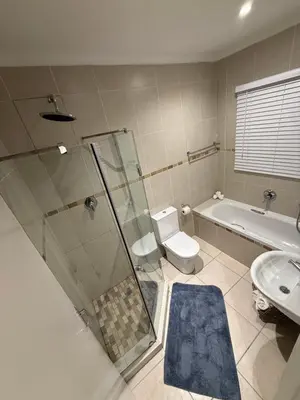 a bathroom with a shower and a toilet and a sink at Three Bedroom Apartment in Cape Town