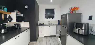 a kitchen with white cabinets and a stainless steel refrigerator at 1 On Sonnet Unit Mia in Cape Town
