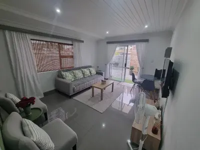 a living room with a couch and a table and a television at 1 On Sonnet Unit Mia in Cape Town