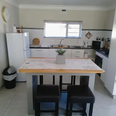 a kitchen with a table and some chairs and a refrigerator at 1 On Sonnet Unit Mia in Cape Town