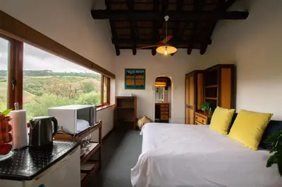 a bedroom with a white bed and a large window at Mountain View and Vineyard View in Suider-Paarl
