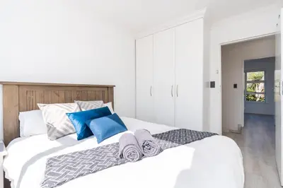 a bedroom with a large white bed with blue pillows at Surfside Haven, 3 Bed Townhouse in Cape Town