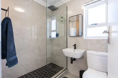 a bathroom with a toilet and a sink and a mirror at Surfside Haven, 3 Bed Townhouse in Cape Town