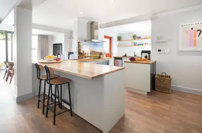 a kitchen with white walls and a counter with bar stools at House La Gratitude - secure parking in Stellenbosch