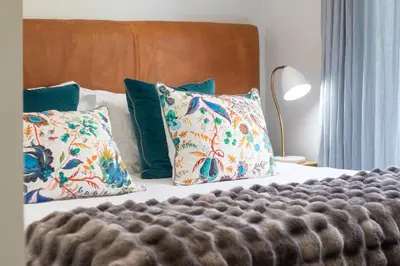 a bedroom with a bed with pillows and a bedskirtspectspects at House La Gratitude - secure parking in Stellenbosch