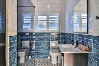 a blue tiled bathroom with a sink and a toilet at Mocha Bay House by the Sea in Bettyʼs Bay
