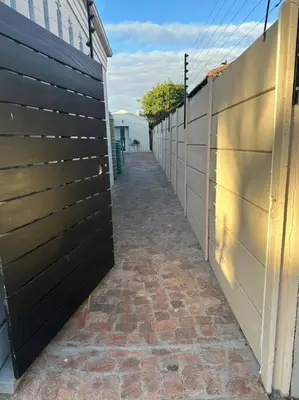 a hallway of a house with a fence and a brick sidewalk at Cozy Private Studio in Cape Town