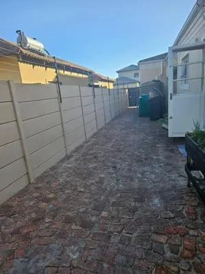 a brick walkway next to a fence next to a house at Cozy Private Studio in Cape Town