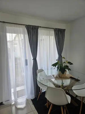 a dining room with a glass table and white chairs at Cozy Private Studio in Cape Town