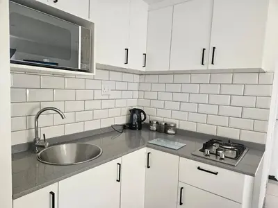 a kitchen with white cabinets and a sink and a microwave at Cozy Private Studio in Cape Town