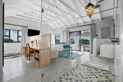 a bedroom with a bed and a desk and a bathroom at Flamingo Bay Manor in Fisherhaven