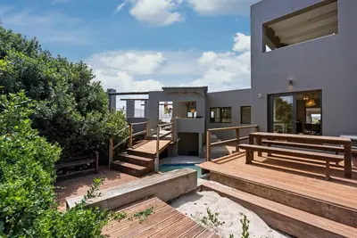 a house with wooden steps and benches in a yard at Flamingo Bay Manor in Fisherhaven