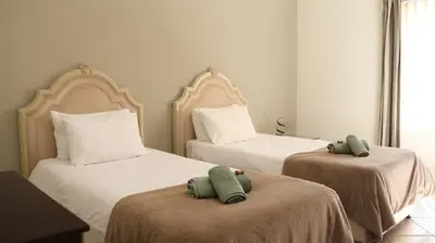 two beds in a room with two green towels on them at Somerset Wineland Apartments & Wellness in Somerset West