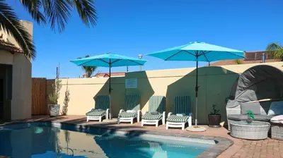 a group of chairs and umbrellas next to a pool at Somerset Wineland Apartments & Wellness in Somerset West