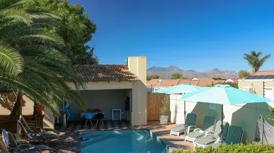 a house with a swimming pool and an umbrella at Somerset Wineland Apartments & Wellness in Somerset West