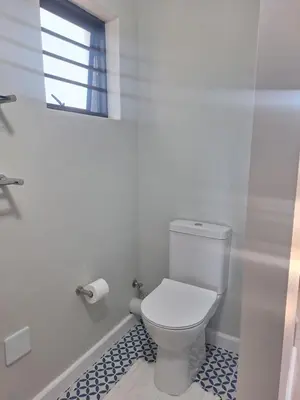 a white bathroom with a toilet and a window at Governor's nest in Cape Town