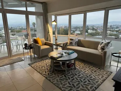 a living room with couches and tables and windows at Clouds in Strand