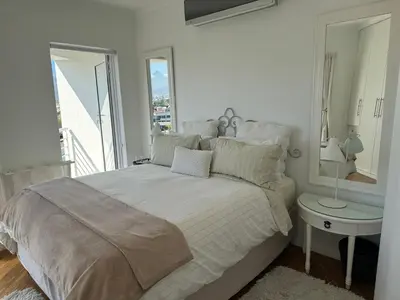 a white bedroom with a large bed and a window at Clouds in Strand