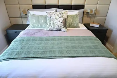 a bed with green and white sheets and pillows at BGS Luxury -Two-bed -Nine Palms in Cape Town