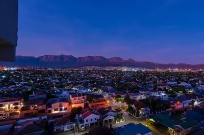 a city at night with mountains in the background at Soete Rus Strand in Cape Town