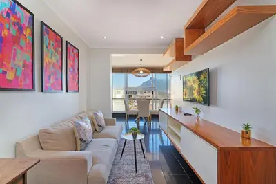 a living room with a couch and a table at Modern Cape Town Beach Apartment in Cape Town