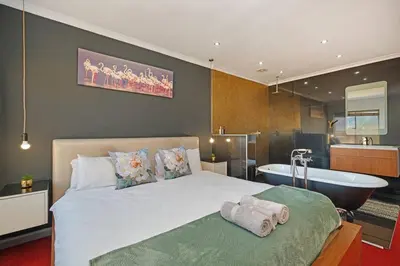 a bedroom with a large bed and a bath tub at Modern Cape Town Beach Apartment in Cape Town