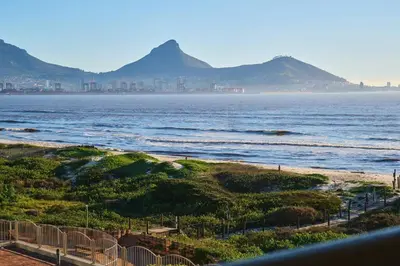 a view of the ocean with mountains in the background at Modern Cape Town Beach Apartment in Cape Town