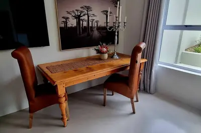 a wooden table with two chairs and a picture on the wall at C'est la Vie 1 in Franschhoek