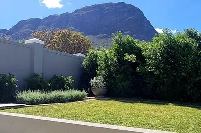 a garden with a fence and a mountain in the background at C'est la Vie 1 in Franschhoek
